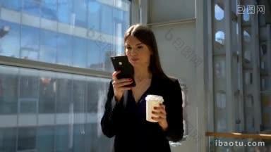 商务女士走在商务中心<strong>拿着</strong>咖啡，用手机上网